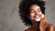 Smiling african american woman in grey background Enjoying. Applying face cream for skin care rutine. Copy space