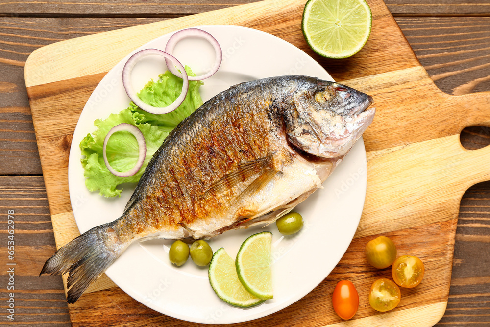 Plate with tasty grilled dorado fish on wooden background
