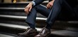 Biznesmen w drogim garniturze rozmyśla siedząc na schodach przed firmą 