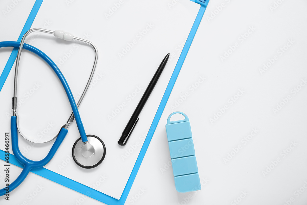 Clipboard, stethoscope and pillbox on grey background
