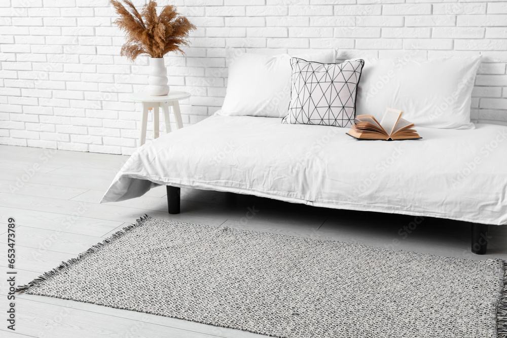 Interior of light bedroom with cozy bed and stylish carpet