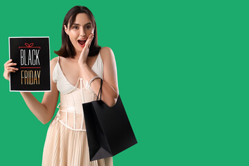 Wall Mural - Surprised young woman with shopping bag on green background. Black Friday sale