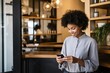© koala studio - Smiling african american woman using mobile phone in coffee shop