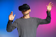 © Maria Vitkovska - Portrait of Asian man playing video game using VR glasses isolated on blue and purple background