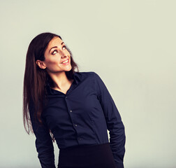 Wall Mural - Happy toothy thinking smiling business woman looking up in blue shirt on blue background with empty copy space. Closeup