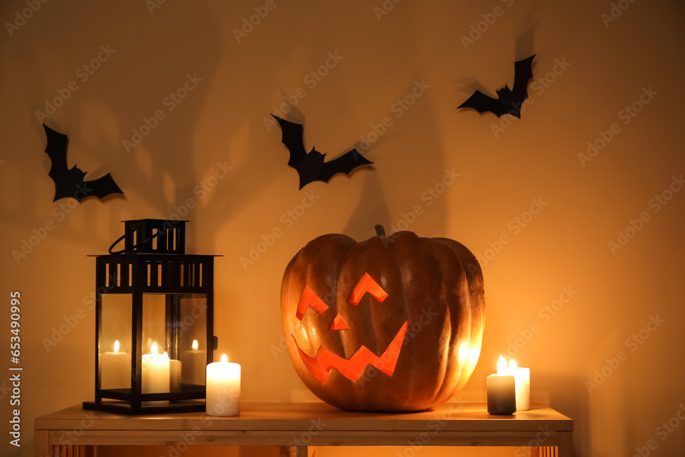 Halloween pumpkin with burning candles on shelf in dark room