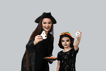 Canvas Print - Little girl and her mother dressed for Halloween with treats on light background