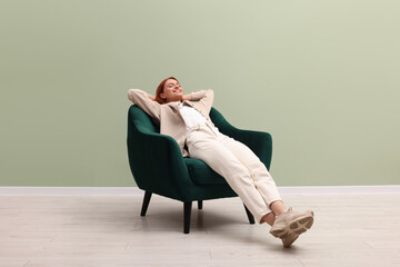 Sticker - Happy young woman relaxing in armchair near light olive wall indoors