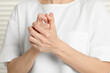 © New Africa - Woman cracking her knuckles on blurred background, closeup. Bad habit
