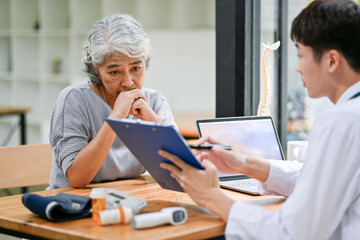 Wall Mural - A stressed Asian retired old lady is consulting treatment plans after surgery with a doctor.