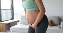 Pregnant Woman With Incontinence And Frequent Urination During Pregnancy. Pregnant Woman Need To Pee Standing By In Livingroom. Pregnancy Concept Video. Health And Wellbeing Of Expectant Mother.