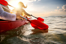 Happy Young Couple Walks On Kayak At Sunset Sea Bay. Close Up Photo Of Paddles In Water