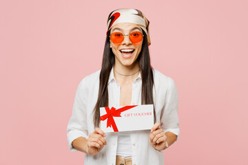 Wall Mural - Young surprised latin woman she wear white shirt casual clothes sunglasses hold gift certificate coupon voucher card for store isolated on plain pastel light pink background studio. Lifestyle concept.