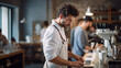 © PaulShlykov - Smiling attractive man barista standing behind the counter at the coffee shop, showing coffee cup