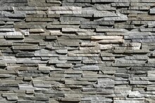 Stone cladding wall made of striped stacked slabs of natural gray and white rocks.  Panels for exterior, background and texture.	