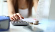 © H_Ko - Focus on tender hands of witty businesswoman sitting indoors and using calculator for counting in important tablet with charts. Office concept. Blurred background