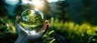 Crystal ball in a woman's hand against a background of green nature. Sunlight. Save the environment. Earth Day concept.
