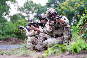 Wall Mural - Military army soldiers tactical team, commando group moving cautiously in forest area, kneeling and looking around, covering comrades, controlling sectors. Commander showing halt or stop hand signal