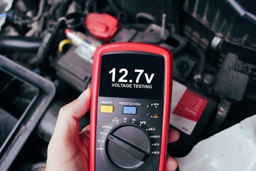 Wall Mural - Car battery voltage testing with a digital multimeter by auto technician, Car voltage current display on black screen of digital multimeter, Car maintenance service concept