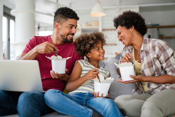 Wall Mural - Happy african american family eating on couch with cardboard boxes in living room interior