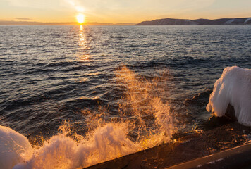Wall Mural - Baikal Lake at sunset in December. Waves crash against an icy pier against the backdrop of the setting sun. Beautiful seascape. Natural background. Travels along the lake shore