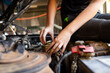 © Austockphoto - Close-up of female mechanic's hands fixing a car part under the hood