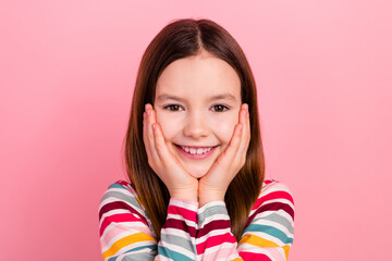 Wall Mural - Photo of cute smile young girl hands touch cheekbones good mood dreamy little kid wear striped shirt isolated on pink color background