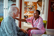 © Marko Geber - Young African American female caregiver consulting her senior patient at home