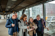 © Marko Geber - Senior group of friends looking at the arrival of their train on a smartphone at the station