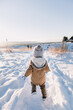 Young boy walking along a snowy track on a sunny day in Winter