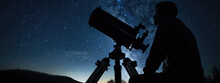 Male Astronomer Looks At The Night Sky Through A Telescope