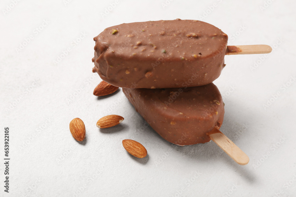 Delicious chocolate covered ice cream and almond nuts on white table