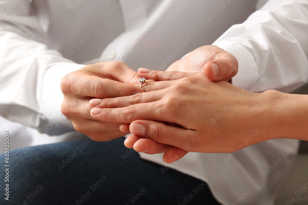 Man putting engagement ring on woman's finger, closeup