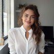 © piotraku - Portrait of a young smiling office worker, with brown hair, wearing a white shirt.