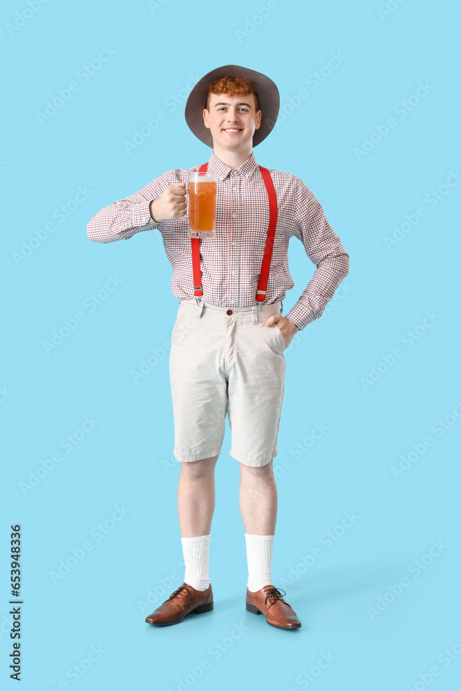 Young man in traditional German clothes with beer on blue background