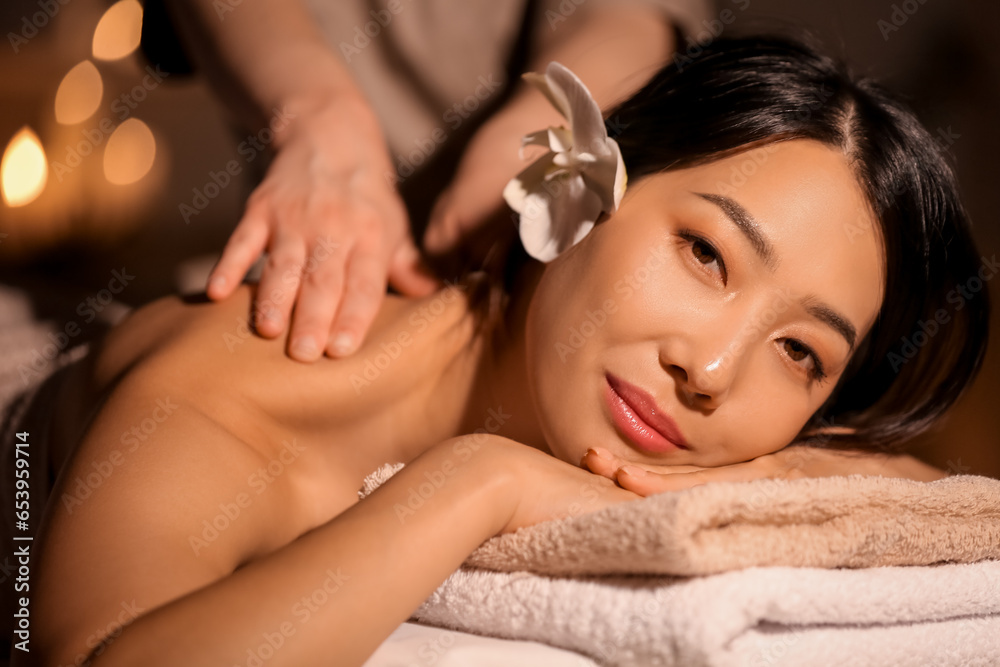 Pretty young Asian woman having massage in spa salon