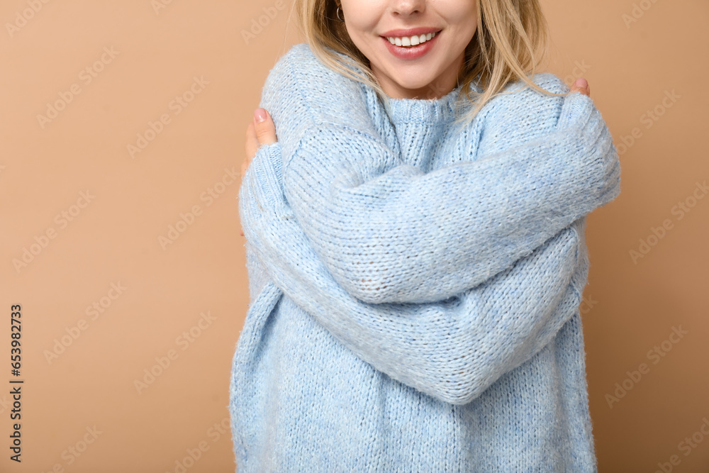 Young woman embracing herself on beige background