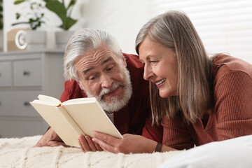 Wall Mural - Lovely senior couple reading book on bed at home