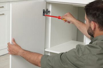 Canvas Print - Man with electric screwdriver assembling furniture indoors, closeup