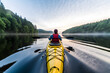 Rear view of woman kayaking in lake with background of beautiful landscape.