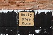 Old vintage ruined brick grunge cracked tiled wall background with text on paper BULLY FREE ZONE, anti bully policy , stop bullying, shame , abuse to create safe and welcoming space in social media