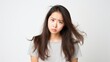 © Pro Hi-Res - Displeased frustrated brunette Asian woman has offended face expression looks sadly being in bad mood wearing gray t-shirt against white background.