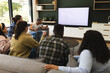 Excited diverse male and female friends watching sport on tv at home, copy space on screen