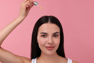 Sticker - Beautiful woman applying hair serum on pink background. Cosmetic product