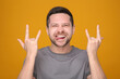 © New Africa - Happy man showing his tongue and rock gesture on orange background