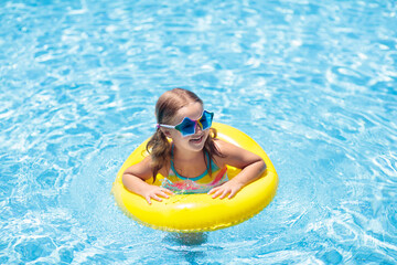 Wall Mural - Child on float in swimming pool. Kids sunglasses.