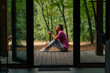 © Guys Who Shoot - a young smiling woman sits sideways on  terrace overlooking the forest and enjoys the silence