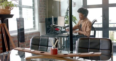 Wall Mural - happy african american man in headphones making live podcast from home, copy space, slow motion