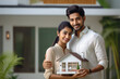 © Neha - Indian couple holding home toy in hand. home loan concept.