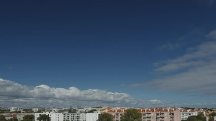 Wall Mural - movement of beautiful clouds in the blue sky over city houses, time lapse video. nice nature backgro
